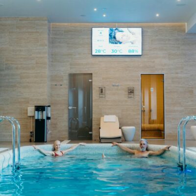 Two adults enjoying leisure time at an indoor swimming pool with spa-like ambiance.